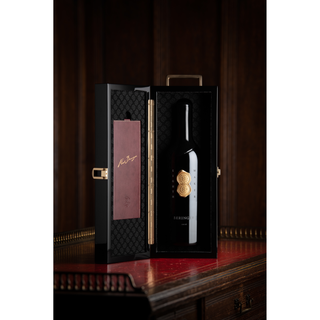 Wine bottle in a black textured box with gold accents on a wooden surface.